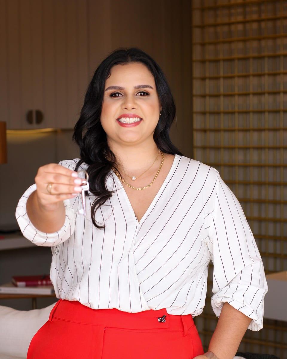 Pamela Gomes sorrindo e segurando as chaves de um imóvel
